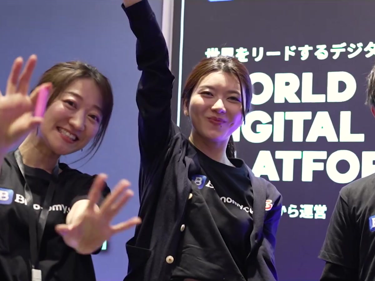 株式会社TEAMZ様 TEAMZ SUMMIT 2025｜出展ブースでカメラに手を振るスタッフ